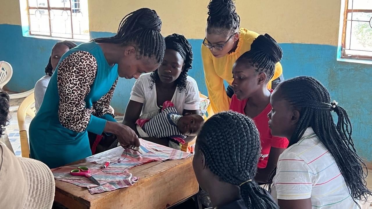 Women gathered around a worktable in a sewing training session.